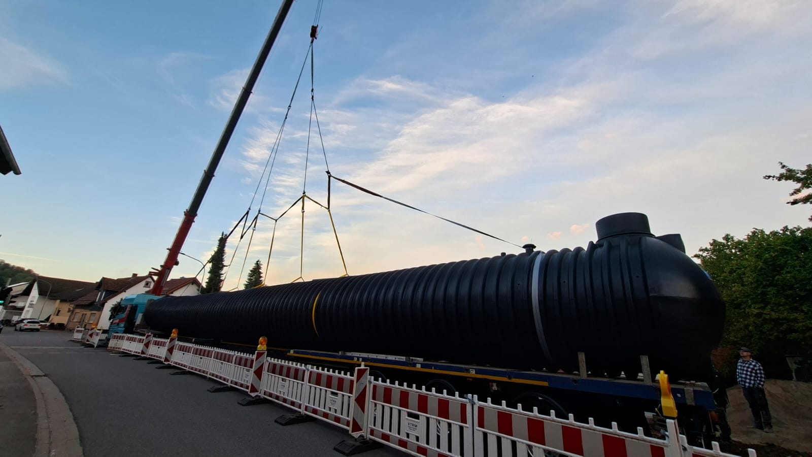 Mobilkran der Karl Scholl GmbH bei Hebearbeiten an einer Bahnstrecke. Der lange Ausleger bewegt eine Last kontrolliert über den Arbeitsbereich und unterstützt die Montagearbeiten vor Ort.