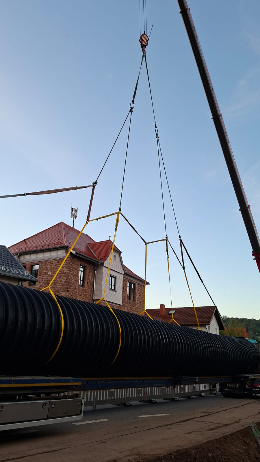 Scholl-Autokran hebt ein Bauteil nahe einer Bahntrasse an. Der Kran positioniert die Last präzise über dem abgesperrten Arbeitsbereich